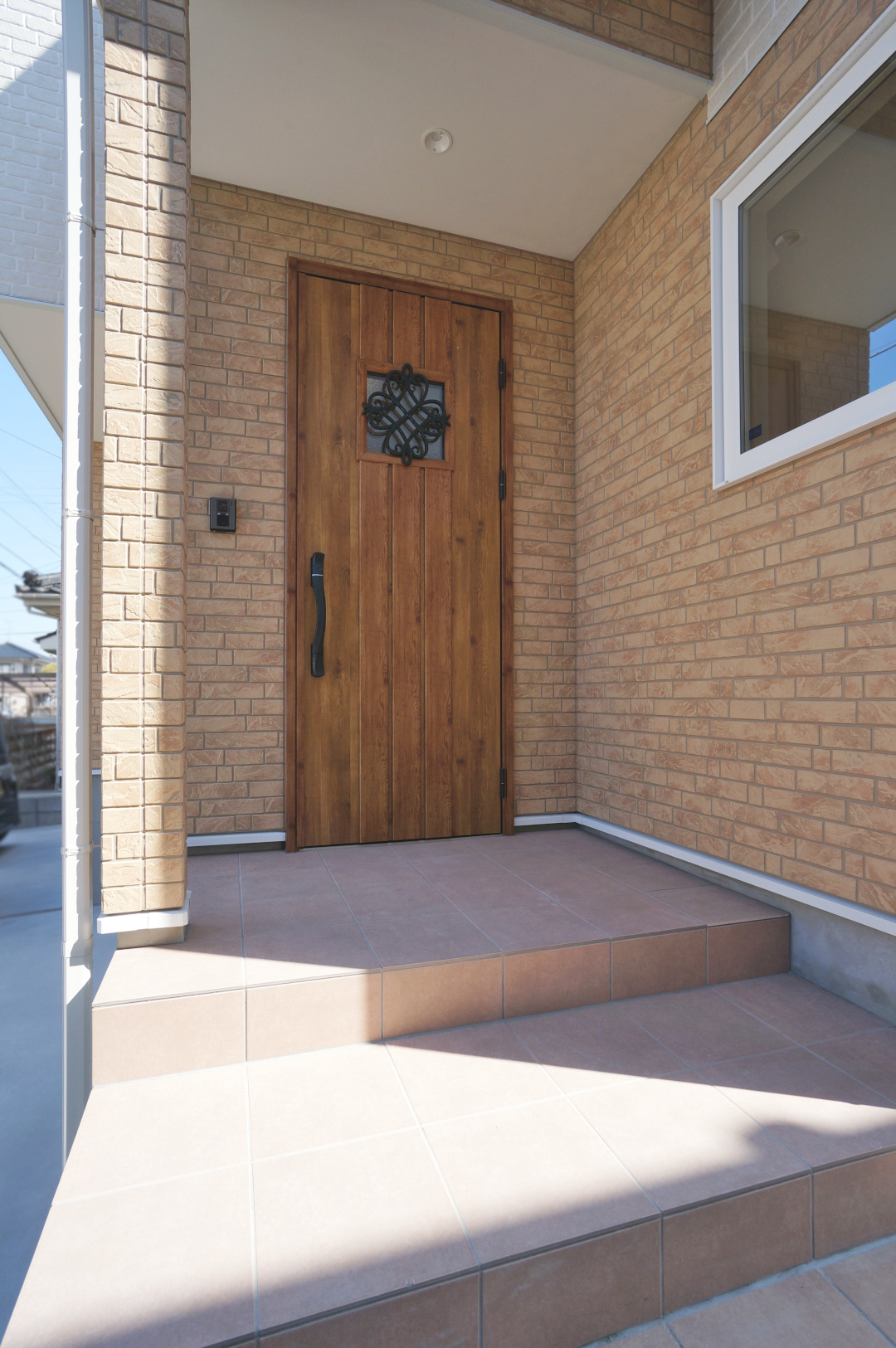 テラコッタ色の玄関タイルとマキアートパインの木目がおしゃれな玄関ドア。カフェ入口のようですね♩